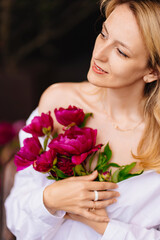 tenderness. a blonde woman in a white shirt and a bouquet of peonies.