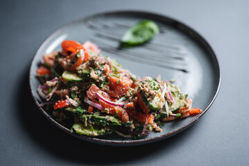 georgian salad with fresh tomato, cucumber, onion and walnut on black background