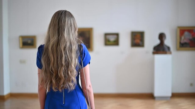 Woman wearing blue dress visiting a museum art gallery