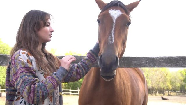 Slow Motion girl standing with her bay horse near paddock