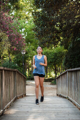 Asian fitness girl running on a wooden bridge in the park