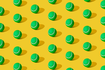 Arranged of green rubber tennis balls on yellow pastel background. Pattern