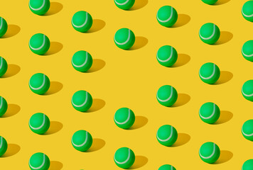 Arranged of green rubber tennis balls on yellow pastel background. Copy space.