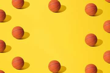 Arranged basketballs on a yellow background. With copy space and pattern.