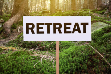 Wooden sign with word Retreat in beautiful forest