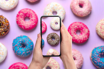 Woman taking picture of delicious doughnuts on violet background, top view - Powered by Adobe