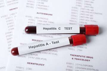 Tubes with blood samples for hepatitis virus test on laboratory form, closeup