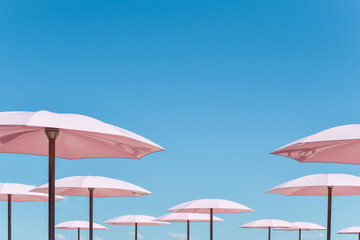 Minimal shot of pink beach umbrellas against blue sky