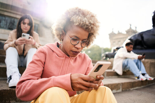 Group Of People Ignoring Each Other Using Phone With Serious Face. Latina Woman Focused On Their Mobile