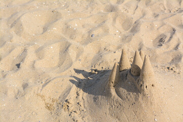 Beach with sand castle on sunny day, above view. Space for text