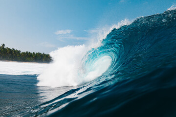 Poderosa ola rompiendo en una paradisiaca playa con palmeras