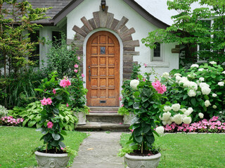 Older house with wood grain front door surrounded by flowers