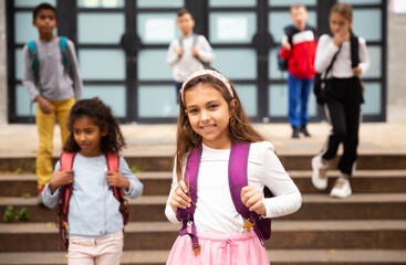 Portrait of smiling schoolgirl standing on the street, kids on background