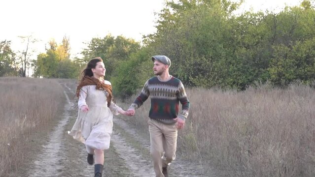 The young boy and girl couple in love running through a meadow hand in hand