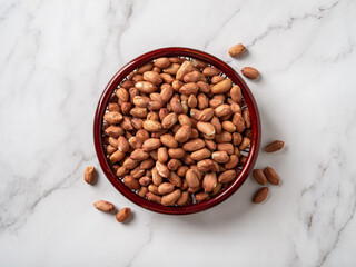 Raw peanut seeds in a wooden bowl on a marble countertop. Dried peeled groundnut as healhy...