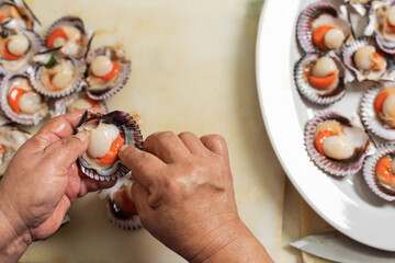 Top view of the hands of a cook presetning seafood on a plate