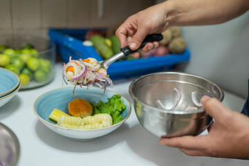 Cook placing ceviche on a porcelain plate to serve
