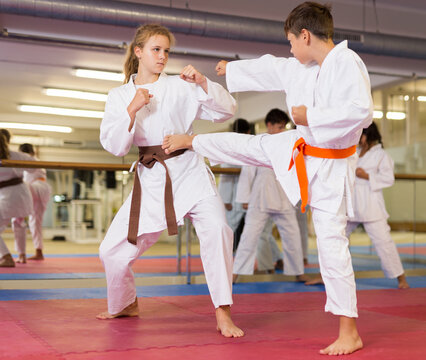 Young diligent positive teenagers practicing new karate moves in pairs in class