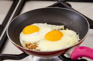 Fried eggs with onions in a pan. Close-up
