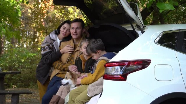 Happy Family Mom and Dad with Kids Enjoying Nature Sitting on the Car 