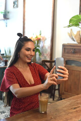 Young woman taking selfie in a coffee shop