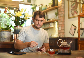 Fototapeta na wymiar Young man eating homemade jam and tea in cafe