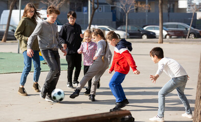 Fototapeta premium Company of glad children playing football on the street. High quality photo