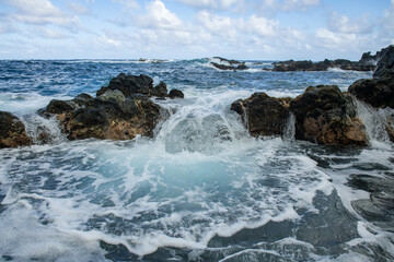 Fototapeta na wymiar Blue sea and rocks storming. Wave spray over rocks. Rocky sea coast.