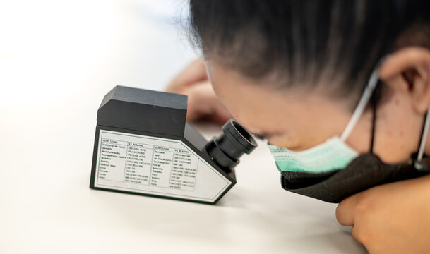 The Gemologist examing the precious stone with the refractometer to separate ohe type of stone.