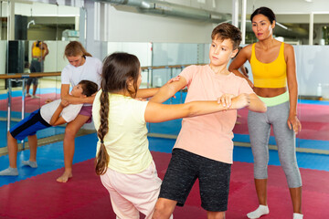 Fototapeta na wymiar Young children working in pair mastering new self-defense moves at gym during group class