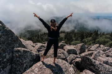 A girl on top of Mount Pidan looks at a beautiful mountain valley in the fog in summer. Travel and tourism. Hiking