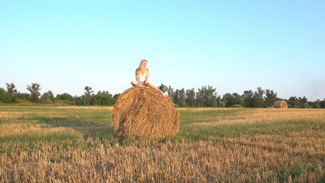 Slow Motion young female sitting on a haystack