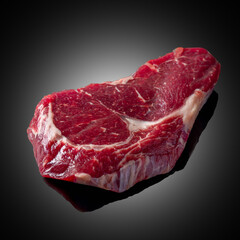  Raw rib eye steak on dark glass with reflection