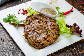 juicy Ribeye steak on plate with pepper sauce on wooden table