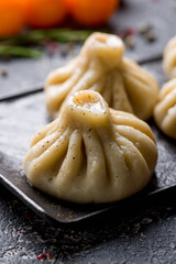 Khinkali with lamb on black plate on dark wooden table macro close up