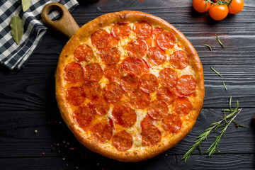 Pepperoni pizza on black wooden table top view