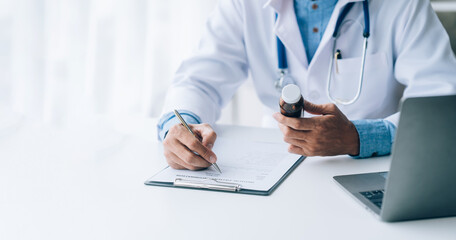 Fototapeta premium Online medical consultation doctor working on laptop computer in clinic office, healthcare, medical service, consultation or education, healthy lifestyle concept