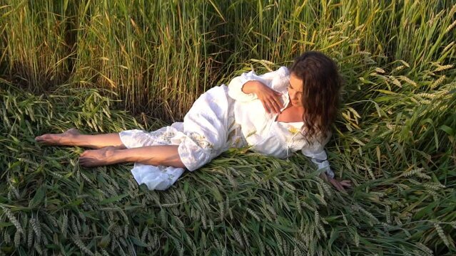 Slow Motion Aerial view of woman lying in the yellow field of wheat