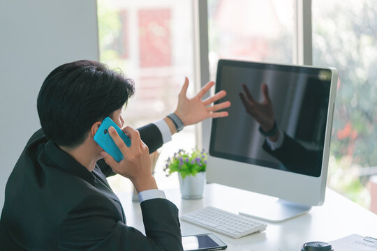 Businessman is shouting on the mobile while looking at blank computer screen in office for mock up.