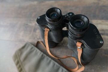 Old military binoculars in a military cap on a wooden table. Close up