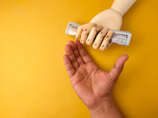 Someone’s hand was asking for money to a wooden hand that was holding a banknote.