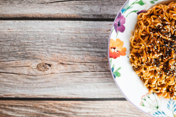 Noodles or spicy Hakka Noodles or Chow Mein in white plate at wood background. Schezwan Noodles is indo-chinese cuisine hot dish with udon noodles, seaweed and chilli sauce.