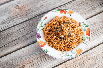 Noodles or spicy Hakka Noodles or Chow Mein in white plate at wood background. Schezwan Noodles is indo-chinese cuisine hot dish with udon noodles, seaweed and chilli sauce.