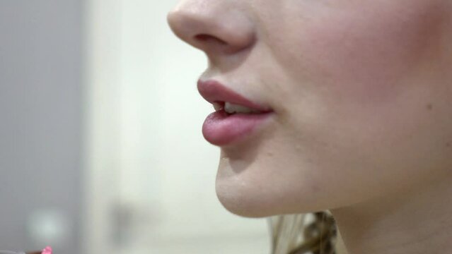 Slow Motion Makeup artist applies lipstick to the clients lips in beauty salon