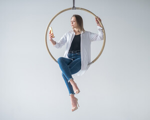 Caucasian woman gymnast on an aerial hoop takes a selfie on a smartphone.  © Михаил Решетников