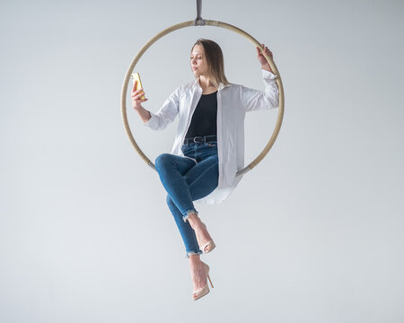 Caucasian woman gymnast on an aerial hoop takes a selfie on a smartphone.