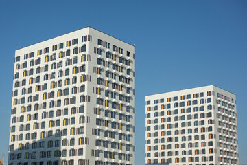 Fototapeta na wymiar Two white buildings against blue sky. Two modern houses. View of city.