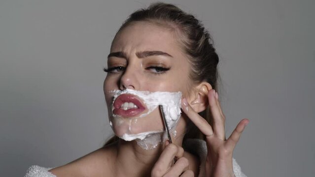 Woman shaving face. Funny young girl shaves her face like a man. Mustache, beard disposable razor.
