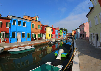 Fototapeta na wymiar Burano Island near Venice with colorful houses and more boats in the navigable canal without people