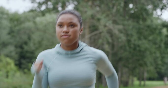 Active young woman running and jogging in a park outside from below. One focused and determined athlete doing cardio exercise while training for a marathon. Runner leading a fit and healthy lifestyle